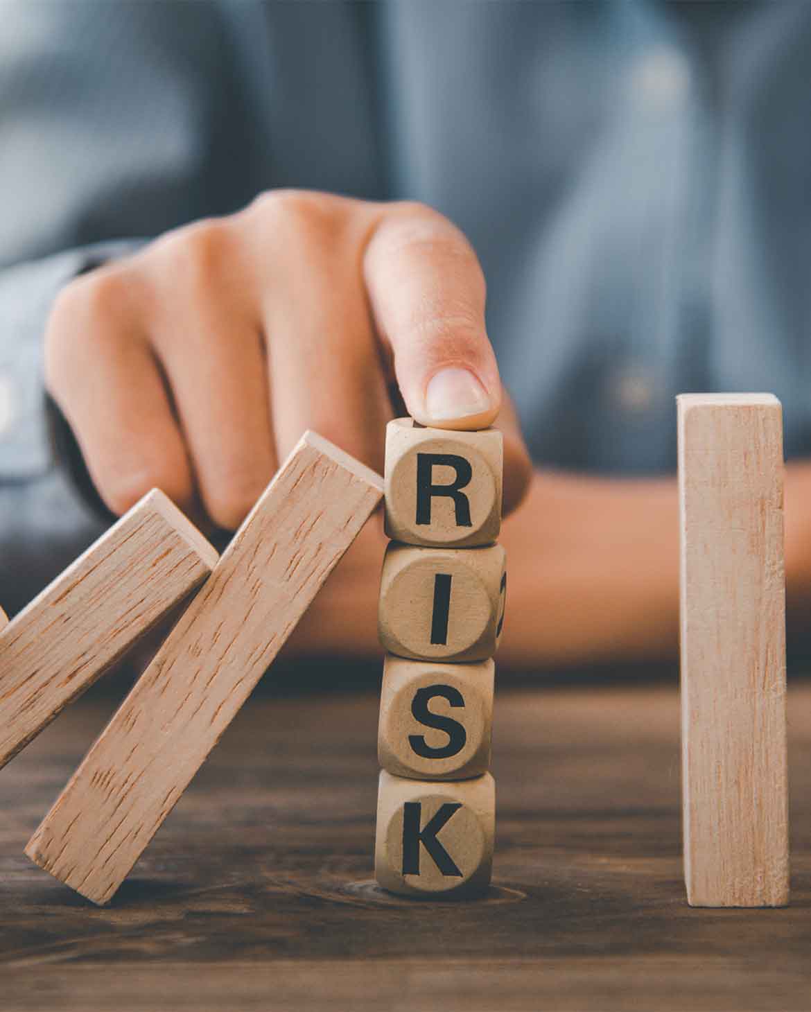 mao-parando-o-efeito-domino-para-proteger-blocos-com-a-palavra-risk-simbolizando-o-gro-gerenciamento-de-riscos-ocupacionais