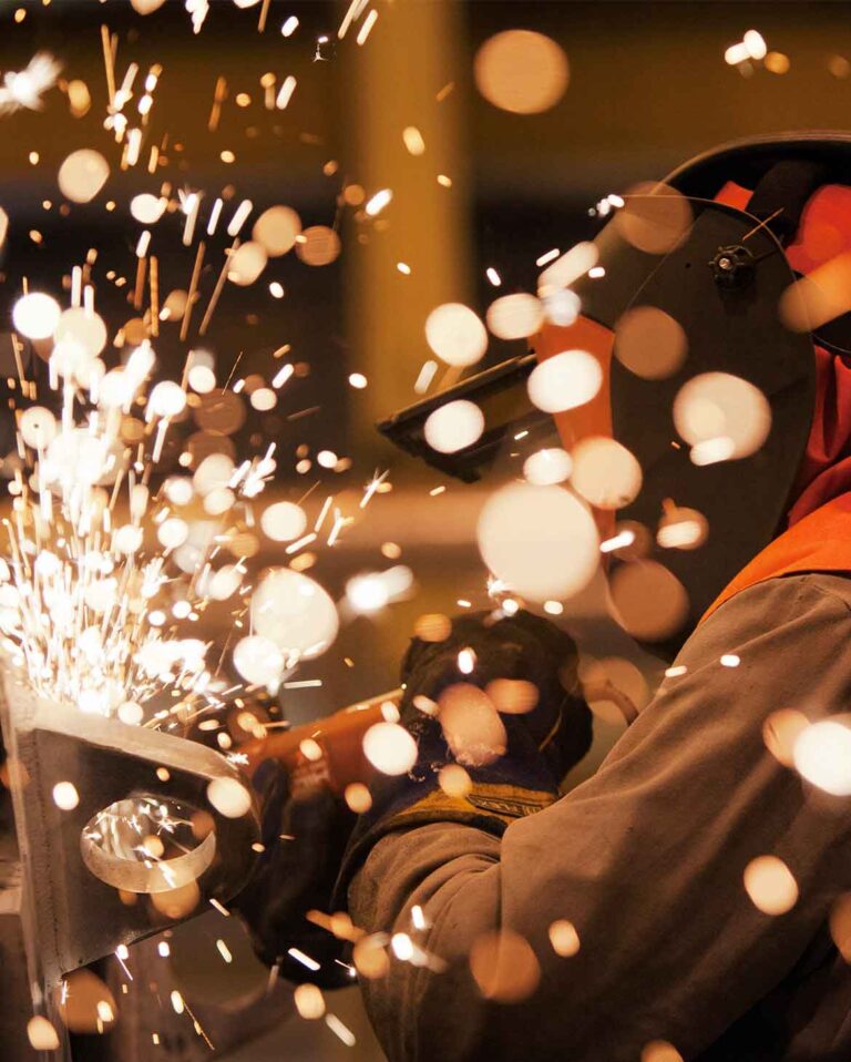 profissional utilizando equipamentos de proteção individual durante operação de soldagem com emissão de faíscas ilustrando a aplicação prática dos controles da permissão de trabalho a quente ptq para mitigação de riscos térmicos.