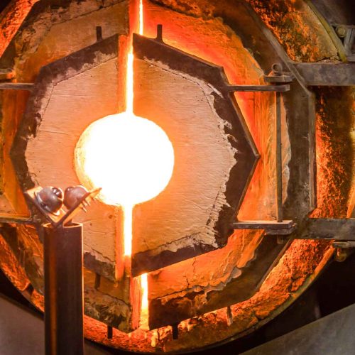 Forno industrial para sopro de vidro com interior incandescente, uma das principais fontes de calor radiante no ambiente de trabalho.