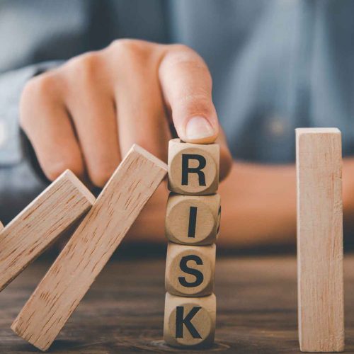 mao-parando-o-efeito-domino-para-proteger-blocos-com-a-palavra-risk-simbolizando-o-gro-gerenciamento-de-riscos-ocupacionais