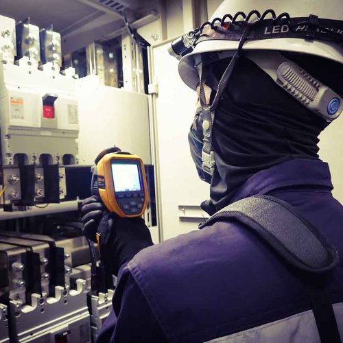 eletricista com balaclava antichama e capacete inspecionando painel eletrico com termovisor para ilustrar o que e atpv na prevencao de arco eletrico