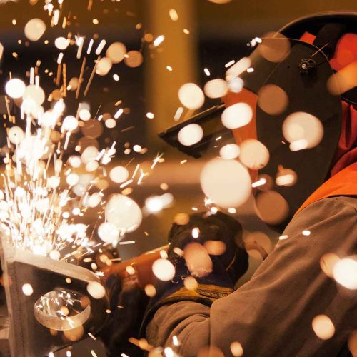 profissional utilizando equipamentos de proteção individual durante operação de soldagem com emissão de faíscas ilustrando a aplicação prática dos controles da permissão de trabalho a quente ptq para mitigação de riscos térmicos.